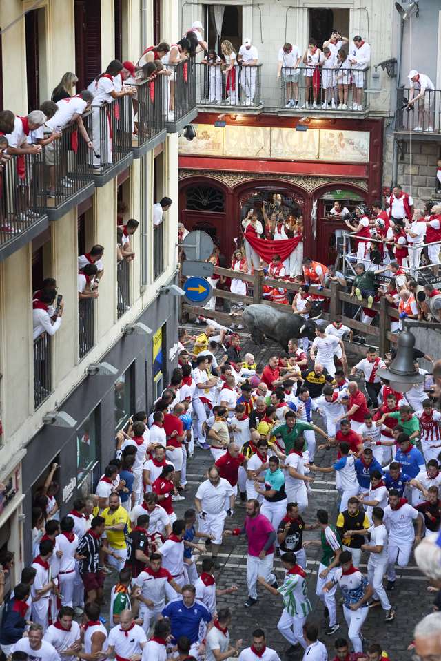 Encierro de San Fermín visto desde un balcón de Pamplona con corredores y toros