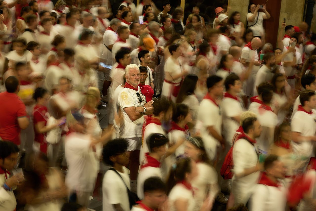 Un hombre quieto entre la multitud vestida de blanco y rojo en San Fermín