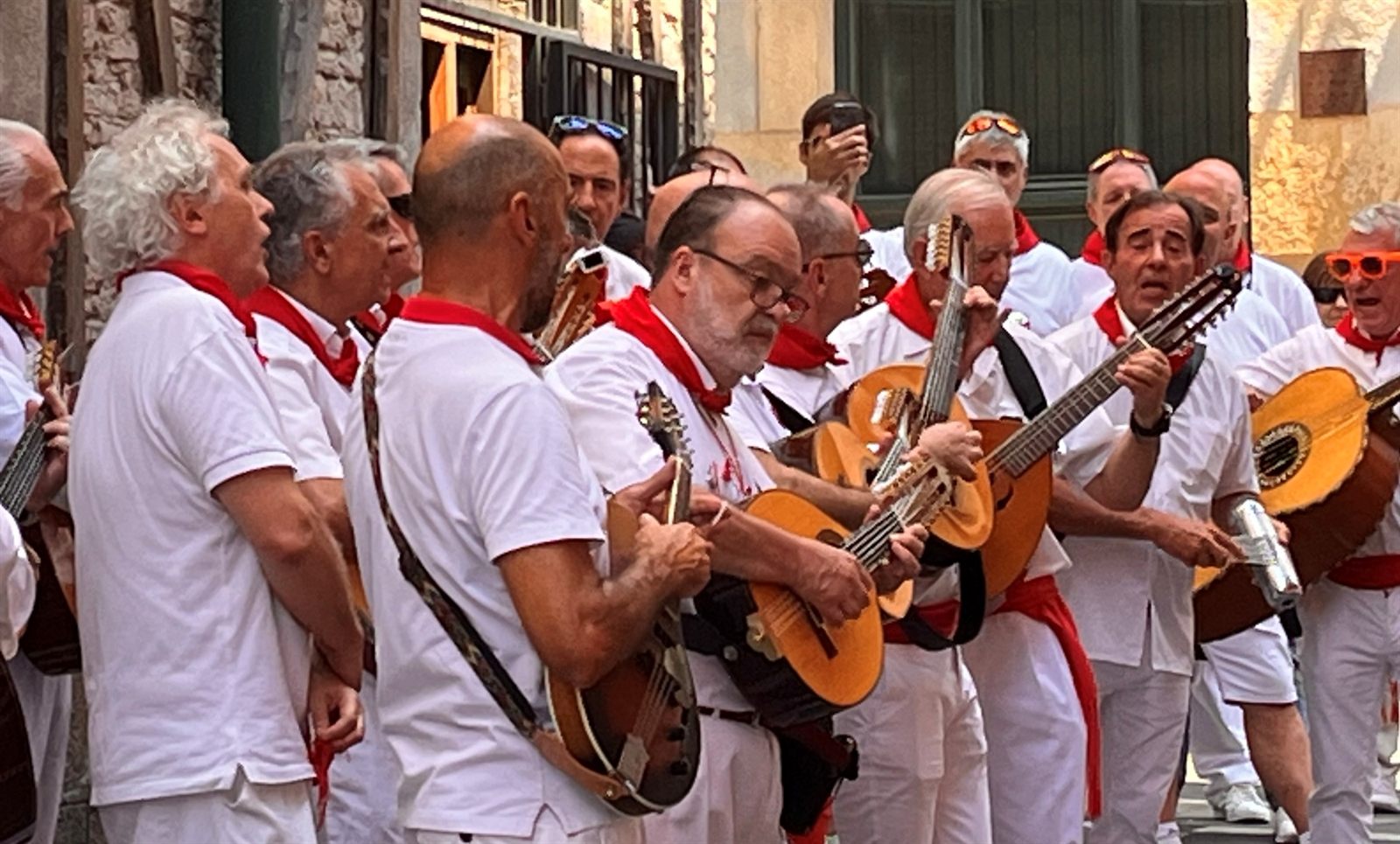 Músicos vestidos de blanco y rojo tocando en la calle durante San Fermín