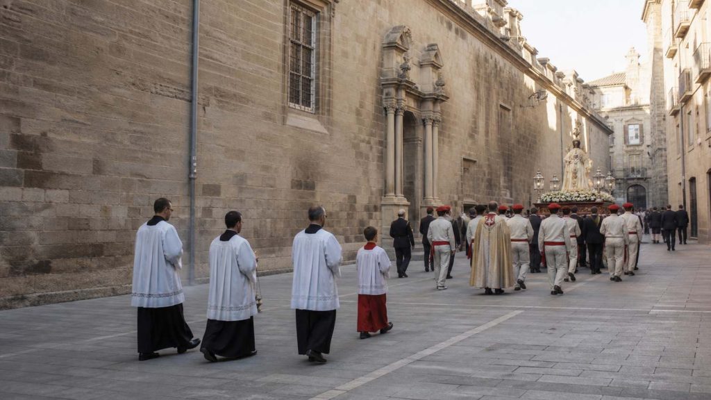 Procesión religiosa de San Fermín avanzando por una calle histórica de Pamplona el 7 de julio
