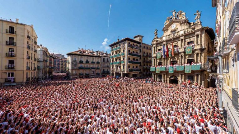 Multitud vestida de blanco y rojo durante el Chupinazo de San Fermín en la Plaza Consistorial de Pamplona