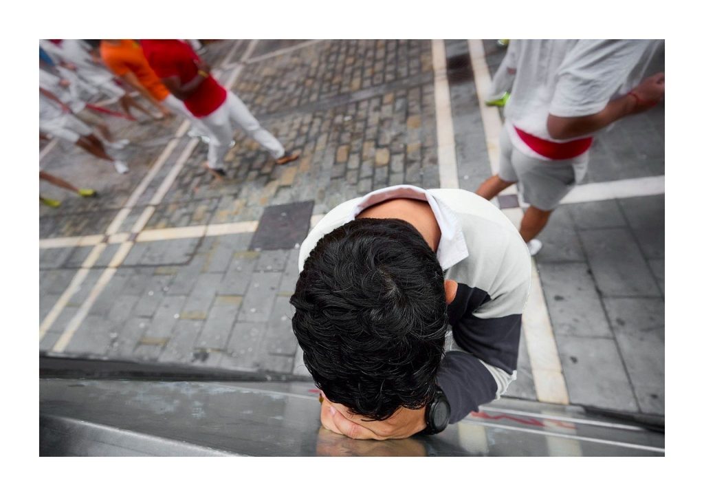 Corredor agachado en el suelo durante el encierro de San Fermín